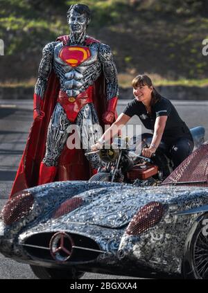 21 avril 2020, Saxe, Dorfhain: Steffi Glück, membre de l'équipe des "Géants of Steel" est assis sur le terrain de la fondation caritative Georado, sur une moto en ferraille, derrière elle se tient 'Superman' et devant elle 'Hercedes SLR 300 Uhlenhaut coupé'. La fondation utilise également l'art pour améliorer la région. À cette fin, le réseau Geoart a été créé, qui unit les artistes au public et les sculptures. Pour un salon, qui ne peut pas avoir lieu sous sa forme originale en raison de la crise de Corona, la fondation a apporté des parties des "Géants de l'acier", des sculptures faites de milliers d'entre moi Banque D'Images