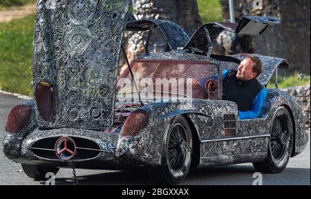 21 avril 2020, Saxe, Dorfhain: Jens Jähnig, responsable de la fondation caritative Georado, siège dans ses locaux de l'entreprise dans un "Mercedes SLR 300 Uhlenhaut coupé", en ferraille. La fondation s'appuie également sur l'art pour améliorer la région. À cette fin, le réseau Geoart a été créé, qui unit les artistes au public et les sculptures. Pour une foire, qui ne peut pas avoir lieu sous sa forme originale en raison de la crise de Corona, la fondation a apporté des parties des "Géants de l'acier", des sculptures faites de milliers de pièces individuelles de ferraille, à Dorfhain. Photo : Robert Michael/dpa-Zentralbild/dpa Banque D'Images