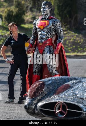 21 avril 2020, Saxe, Dorfhain: Steffi Glück, membre de l'équipe des "Géants de l'acier" se tient sur le terrain de la fondation caritative Georado, à côté d'une sculpture "superman" faite de ferraille, devant laquelle se trouve un "Mercedes SLR 300 Uhlenhaut coupé. La fondation s'appuie également sur l'art pour améliorer la région. À cette fin, le réseau Geoart a été créé, qui unit les artistes au public et les sculptures. Pour un salon, qui ne peut pas avoir lieu sous sa forme originale en raison de la crise de Corona, la fondation a apporté des parties des "Géants de l'acier", sculptures faites de milliers de personnes Banque D'Images