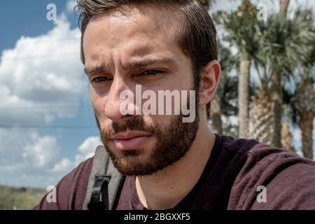 Un homme portant une chemise rouge se retrouve dans la vie, tandis qu'il se soule dans sa sombre journée ensoleillée sur un banc de parc Banque D'Images