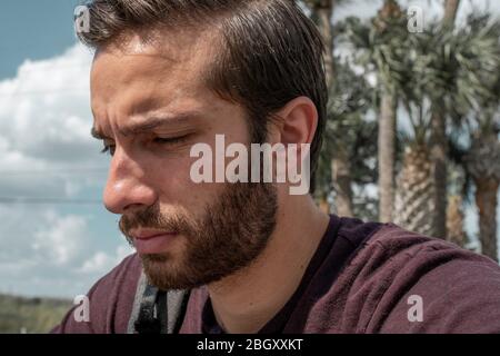 Un homme portant une chemise rouge se retrouve dans la vie, tandis qu'il se soule dans sa sombre journée ensoleillée sur un banc de parc Banque D'Images