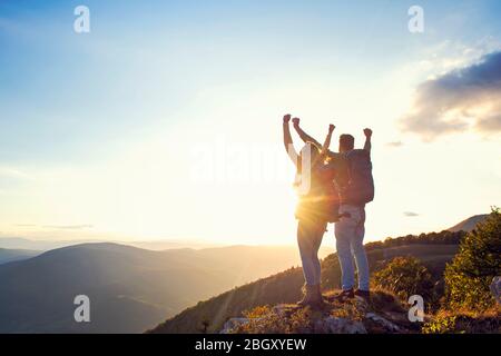heureux couple homme et femme touriste au sommet de la montagne au coucher du soleil dehors pendant une randonnée en été Banque D'Images