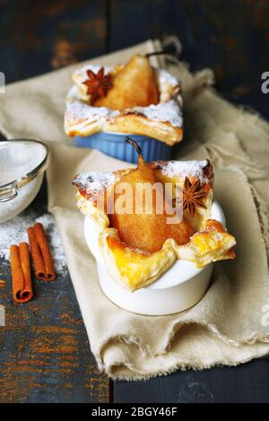 Petites tartes de poire en tasses, sur table en bois Banque D'Images