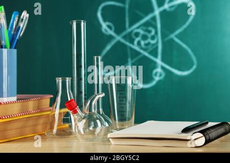 Bureau en classe chimie avec tubes à essai sur fond vert de tableau noir Banque D'Images