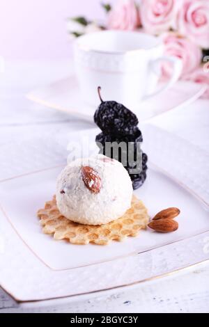 Dessert avec pruneaux et crème glacée et bouquet de roses sur fond de table en bois couleur Banque D'Images