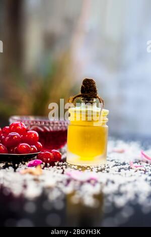 Gros plan de cerises douces fraîches ou Prunus avium avec son huile, son jus et son thé sur une surface noire brillante avec des cerises fraîches brutes. Banque D'Images