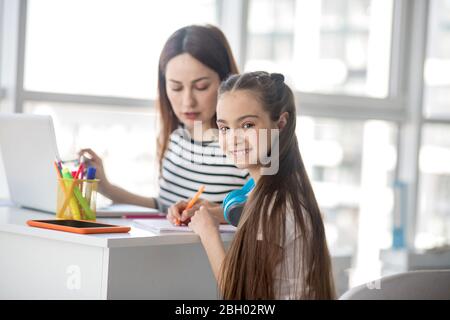 Maman et fille travaillant ensemble à la table à la maison. Banque D'Images