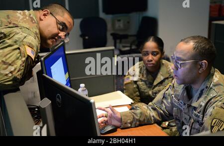 Les membres de la Garde nationale de l'Armée de New York discutent des procédures à la ligne d'assistance Coronavirus, centre d'appel à Hawthorne, N.Y., 16 mars 2020. Le département de la santé de l'État de New York a créé une ligne d'assistance téléphonique sans frais pour le coronavirus (1-888-364-3065). (ÉTATS-UNIS Photo de la Garde nationale aérienne par Sean Madden, agent principal de l'aviation) Banque D'Images