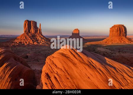 Coucher de soleil sur Monument Valley, avec deux rochers de grès rouge sculptés au premier plan Banque D'Images
