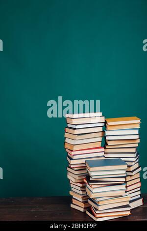de nombreuses piles de livres éducatifs dans la bibliothèque universitaire sur un fond vert Banque D'Images