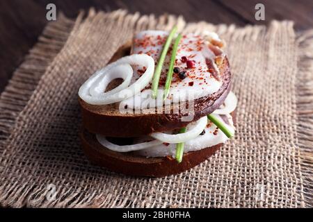 Sandwichs avec lard et oignon sur un chiffon en toile de sac à la table près Banque D'Images