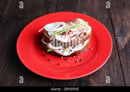 Sandwichs avec lard et oignon sur plaque sur fond en bois Banque D'Images