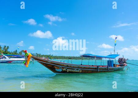 Bateau à queue de logail thaïlandais avec décorations sur l'arc. Bateau amarré au large de la rive sablonneuse. Paysage tropical Banque D'Images