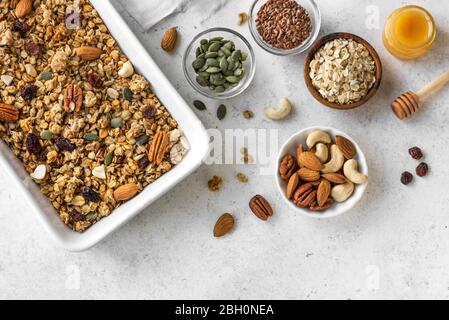 Granola rôtie avec ingrédients - noix, raisins secs, miel et graines. Granola maison pour un petit déjeuner sain sur blanc, vue sur le dessus. Banque D'Images