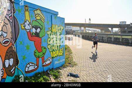 Brighton UK 23 avril 2020 - un coureur passe par l'art du graffiti à Black Rock à Brighton lors d'une belle journée chaude et ensoleillée pendant les restrictions de verrouillage pendant la crise pandémique de Coronavirus COVID-19 . Les températures devraient atteindre 25 degrés dans certaines régions du Sud-est aujourd'hui . Crédit: Simon Dack / Alay Live News Banque D'Images