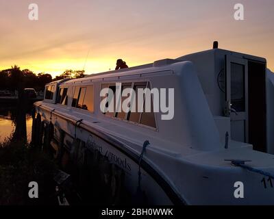 Une femme se détendant sur un bateau de vacances amarré à Stalham sur les norfolk broads sous un coucher de soleil doré Banque D'Images