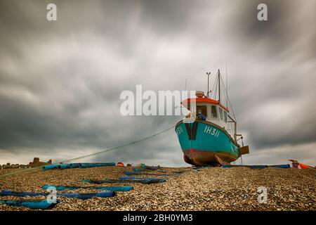 Une photo d'exposition longue d'un bateau de pêche rustique reposant sur une plage de galets à Aldborough, sur la côte du Suffolk Banque D'Images