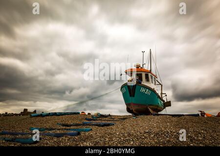 Une photo d'exposition longue d'un bateau de pêche rustique reposant sur une plage de galets à Aldborough, sur la côte du Suffolk Banque D'Images