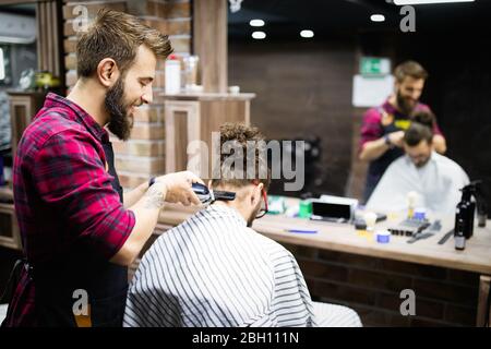 Homme ayant une coupe de cheveux avec une tondeuse à cheveux dans le salon de barbershop Banque D'Images