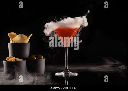 Magnifique cocktail isolé sur fond noir avec fumée de glace sèche. Vapeur blanche dans un verre froid, avec hors-d'œuvre et espace pour copier le texte. Idéal pour Banque D'Images