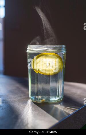 verre avec eau chaude et tranches de citron Banque D'Images