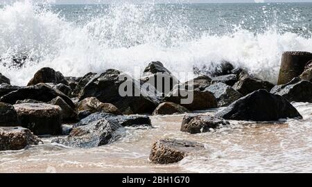 Les vagues de l'océan Atlantique s'écrasent sur des rochers qui font partie d'une jetée au large de la côte de Fire Island New York USA. Banque D'Images