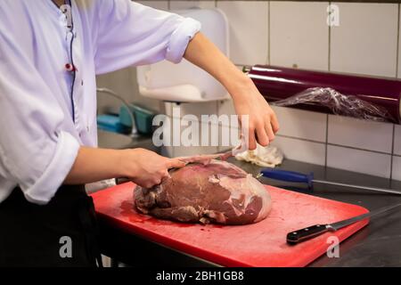 Chef coupant et préparant un grand morceau de viande à cuire, dans la cuisine. Broyeur de viande professionnel, hachée pour pain de viande Banque D'Images