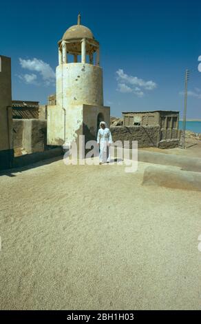 Qatar, Khor, Man sur le toit de l'ancienne mosquée dans le village de pêcheurs, le toit a une couche de petites coquilles pour le garder frais. Banque D'Images