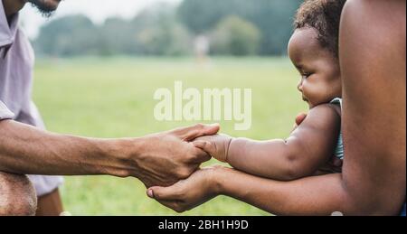 Une famille africaine heureuse possède des mains ensemble en plein air pendant la fête des mères - maman, père et fille ayant des moments d'appel d'offres dans le parc vert de la nature - Amour an Banque D'Images
