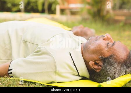 Les hommes âgés pratiquant le yoga - Shavasana ou corps pose est la fin d'une classe ou d'une pratique - yoga pour les personnes âgées, actif sain concept de personnes âgées. Banque D'Images