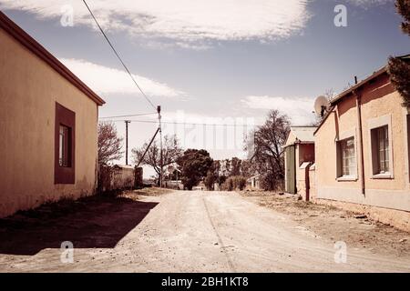 Vue sur une route de terre traversant une petite ville dans la région rurale de Karoo en Afrique du Sud Banque D'Images