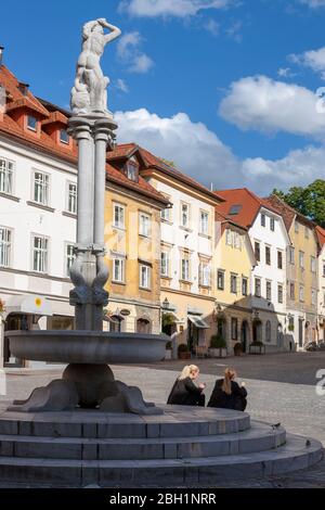 Deux filles s'assoient sur les marches de la fontaine Hercules au pied de Gornji Trg, Ljubljana, Slovénie Banque D'Images