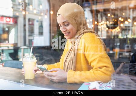 Portrait d'une jeune femme avec smoothie et smartphone dans un café Banque D'Images