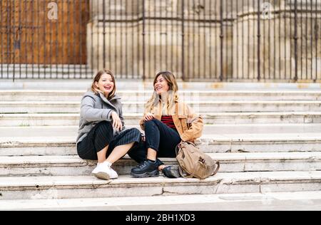 Deux jeunes femmes heureuses assises dans les escaliers de la ville Banque D'Images