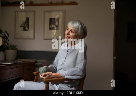 Portrait d'une femme âgée se détendant avec une tasse de thé à la maison Banque D'Images