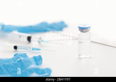 Flacon à médicaments, gants en caoutchouc bleu, seringues et papiers sur fond clair. Développement d'un vaccin contre le coronavirus. Équipement médical, 2019-nCoV liquide dru Banque D'Images