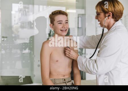 Médecin examinant un adolescent avec un stéthoscope Banque D'Images