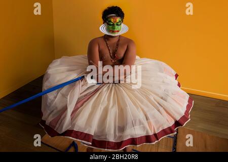 Danseuse Kathakali assise en portant son costume avant la performance. Banque D'Images