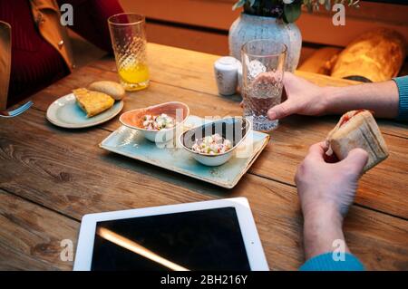 Deux personnes assises au restaurant, manger et prendre des repas, avec tablette numérique sur la table Banque D'Images