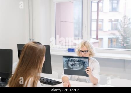 Dentiste parlant des résultats de radiographie au patient Banque D'Images