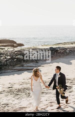 Couple de mariés heureux marchant sur la plage Banque D'Images