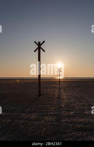 Danemark, Romo, Silhouettes de marqueurs de distance sur la plage côtière au coucher du soleil Banque D'Images