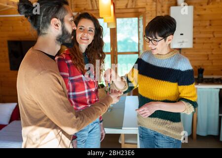 Accueillir un jeune couple dans une cabine à la campagne, en remettant la clé de la maison Banque D'Images