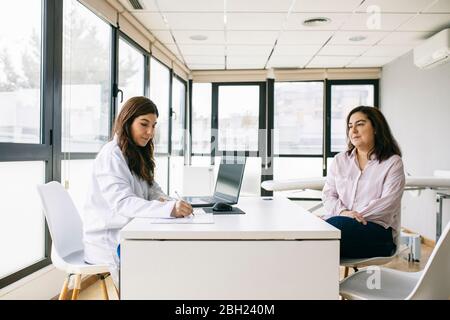 Médecin prenant des notes lors d'une consultation en pratique médicale Banque D'Images