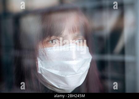 Portrait de femmes âgées portant un masque à la maison, regardant par la fenêtre Banque D'Images