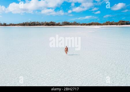 Femme marchant sur une banque de sable blanc dans la mer, Bahamas, Caraïbes Banque D'Images