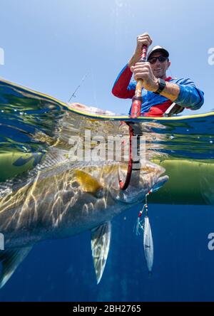 Photo en deux parties d'un homme heureux dans un kayak qui attrape un poisson Banque D'Images