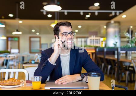 Portrait d'un homme d'affaires heureux au téléphone dans un café Banque D'Images