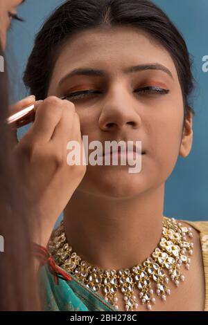 Artiste de maquillage mettant le eyeliner sur l'œil du danseur de kathak. Banque D'Images
