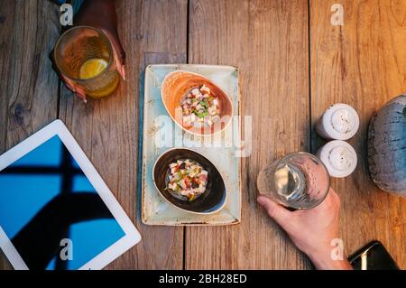 Deux personnes assises au restaurant, manger et prendre des repas, avec tablette numérique sur la table Banque D'Images